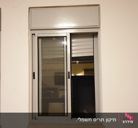 חלון עם תריסים חצי פתוחים על קיר לבן
